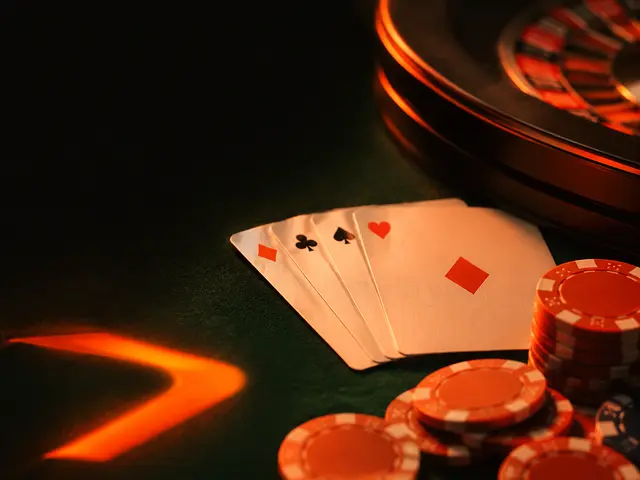 Mesa de casino con ruleta, naipes y fichas bajo luz naranja